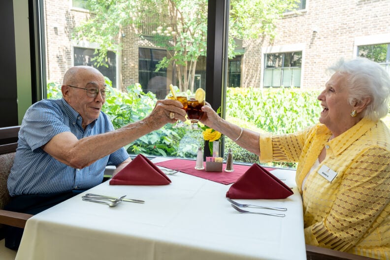 Senior Couple Enjoying Their Drinks in a Bright Dining Area of an Independent Living Facility Senior Couple Enjoying Their Drinks in a Bright Dining Area of an Independent Living Facility