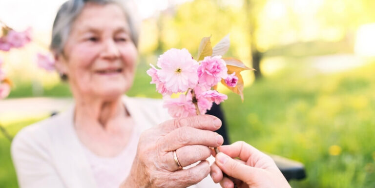 Elderly Woman Receiving Spring Flowers Outdoors at an Independent Living Facility