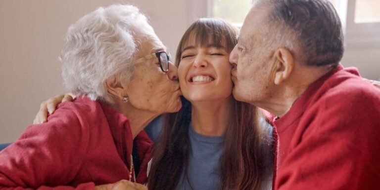 Elderly Couple Kissing Granddaughter on Cheeks at Independent Living Facility